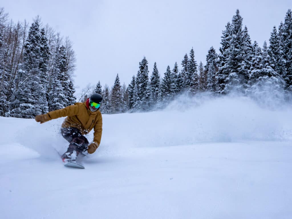 A snowboarder kicks up powder on a snowy day