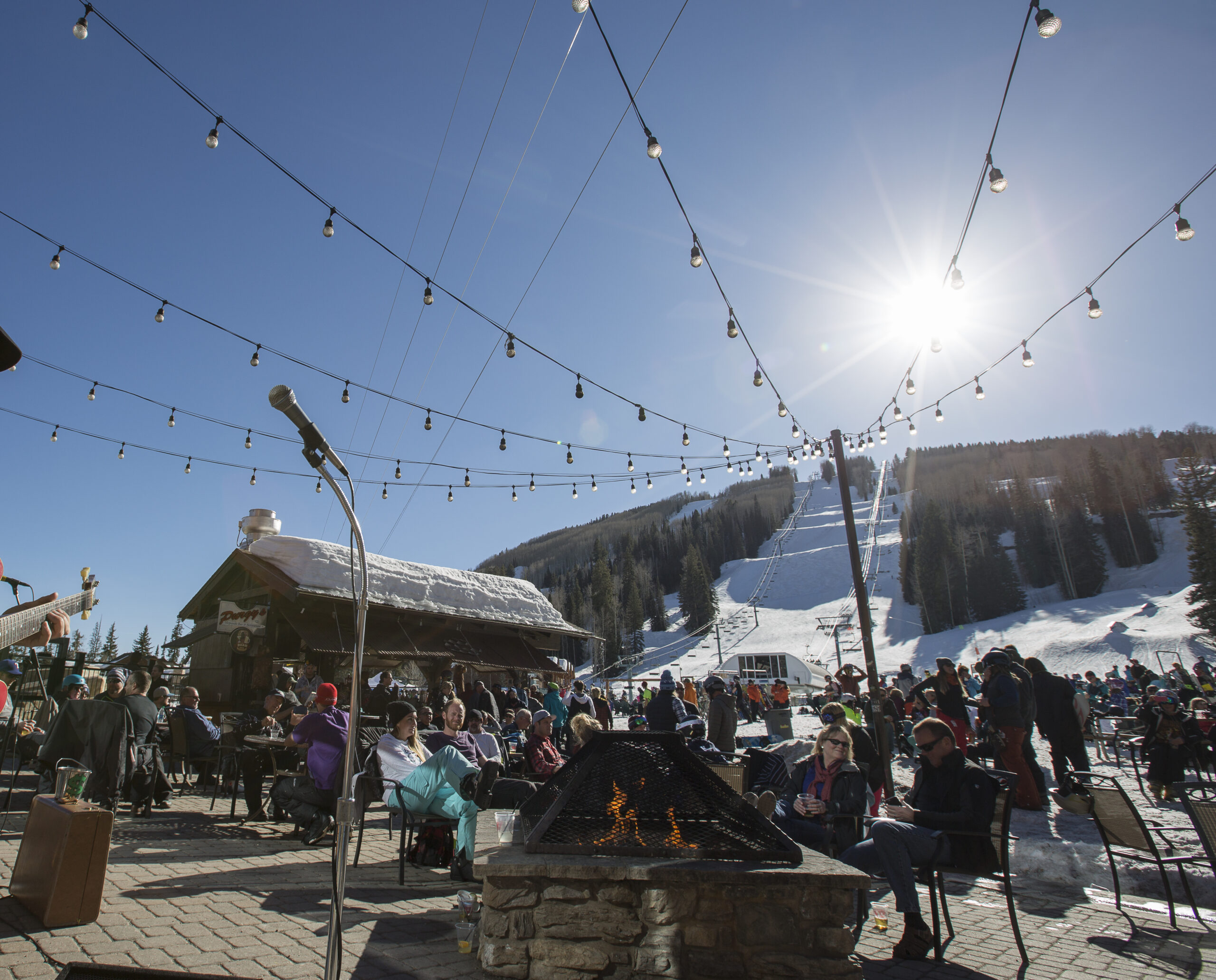 The sun shines over Purgy's Patio with snowy slopes in the background