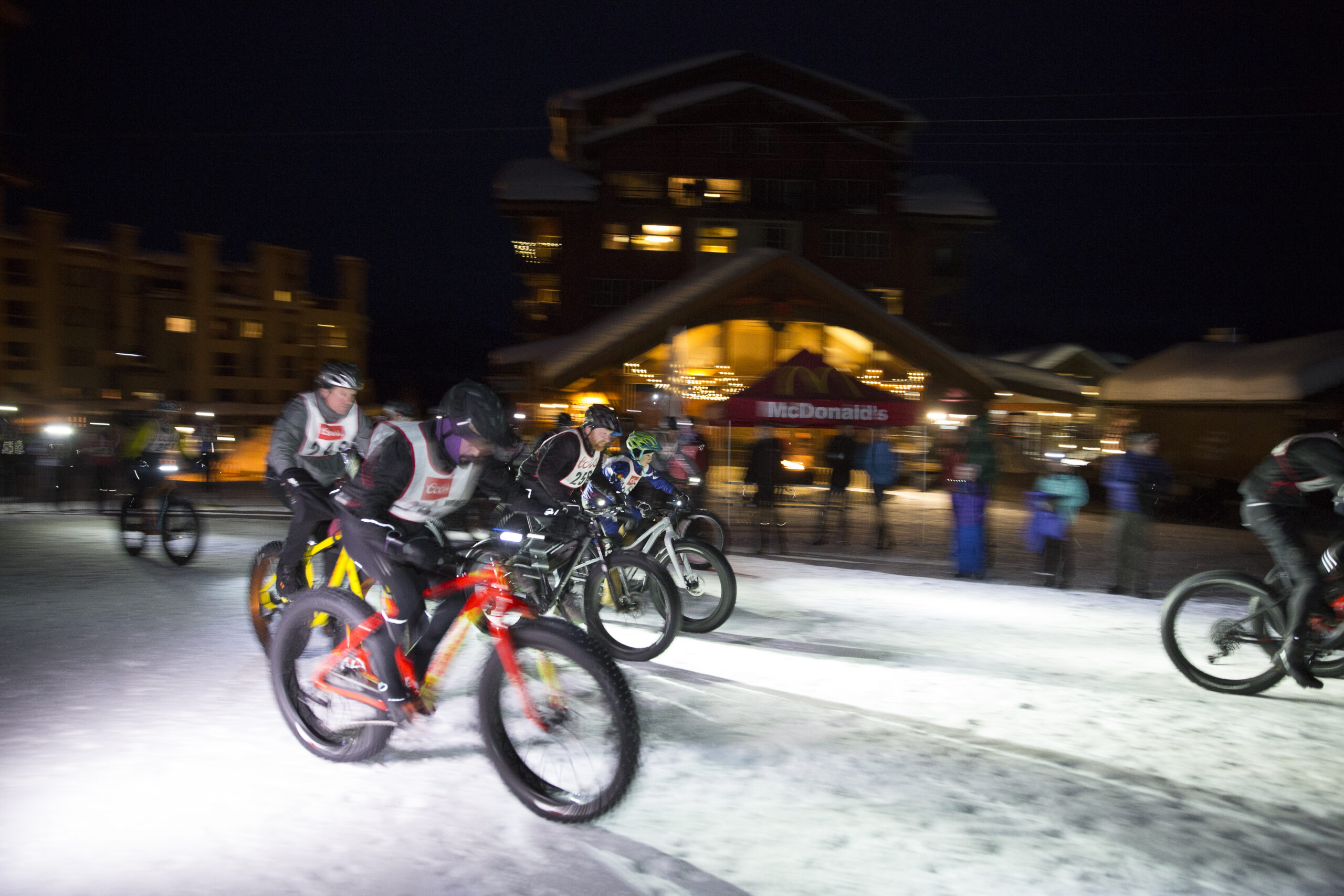 Racers on fat bikes set off in the dark during the McDonald's Winter Triathlon