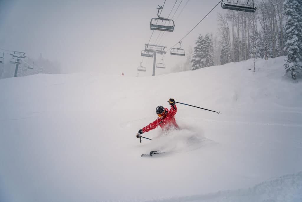 A skier rides down through powder