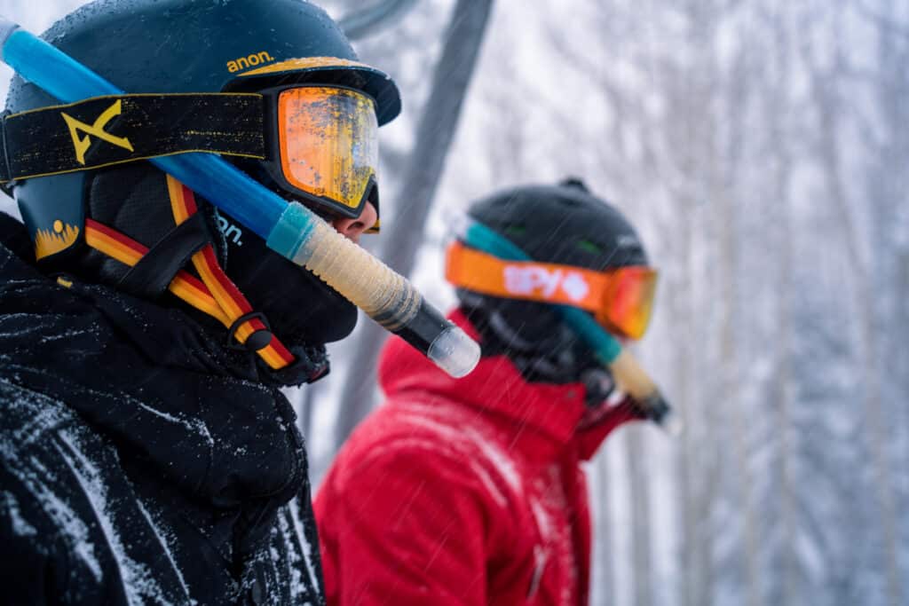 Two people sit on the ski lift in snorkels