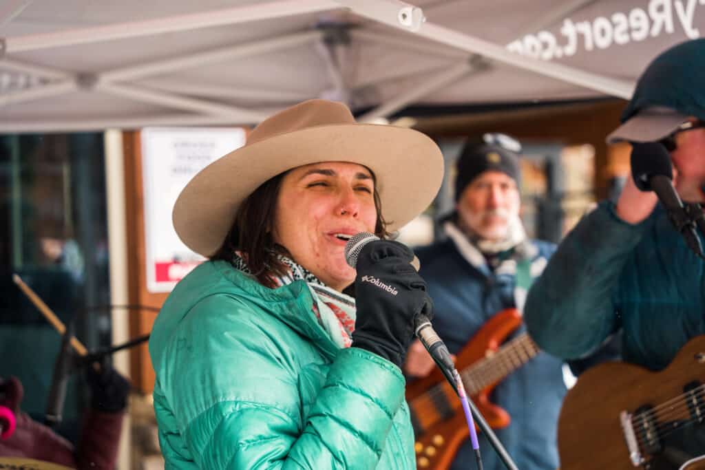 A woman in a green coat sing into a microphone