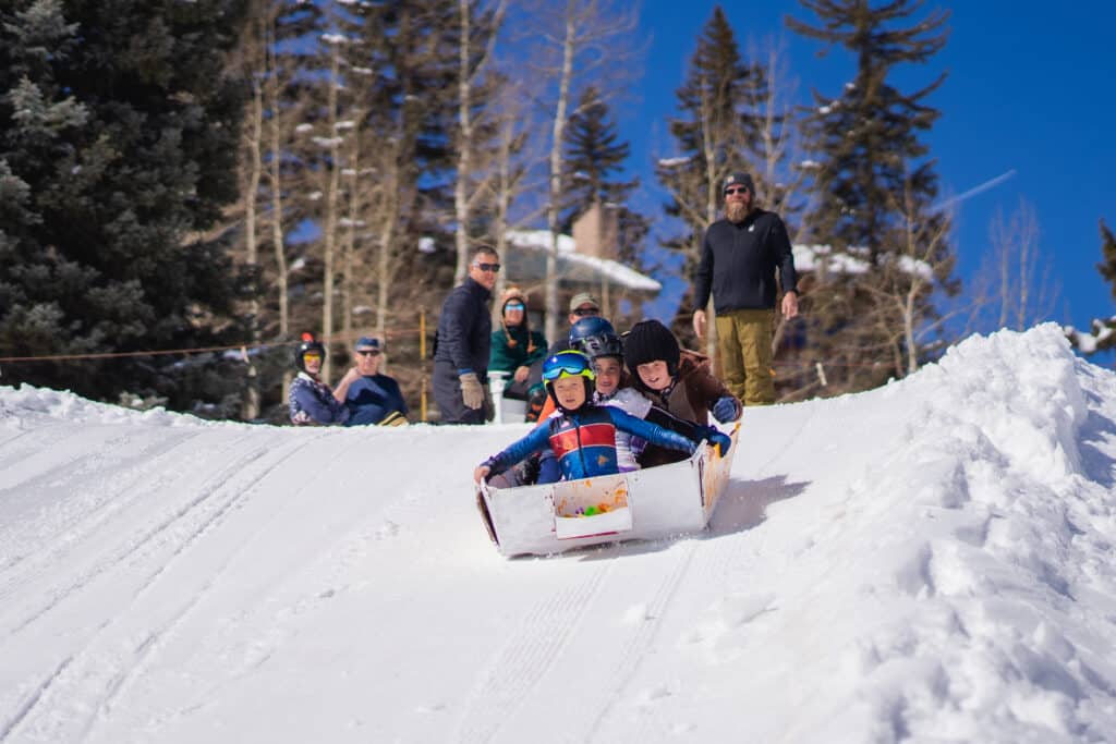 A group of kids soaring down the hill in their cardboard derby