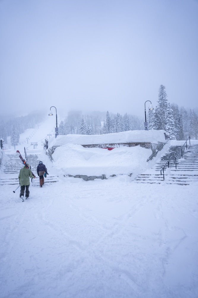 A skier and a boarder walk to the base area