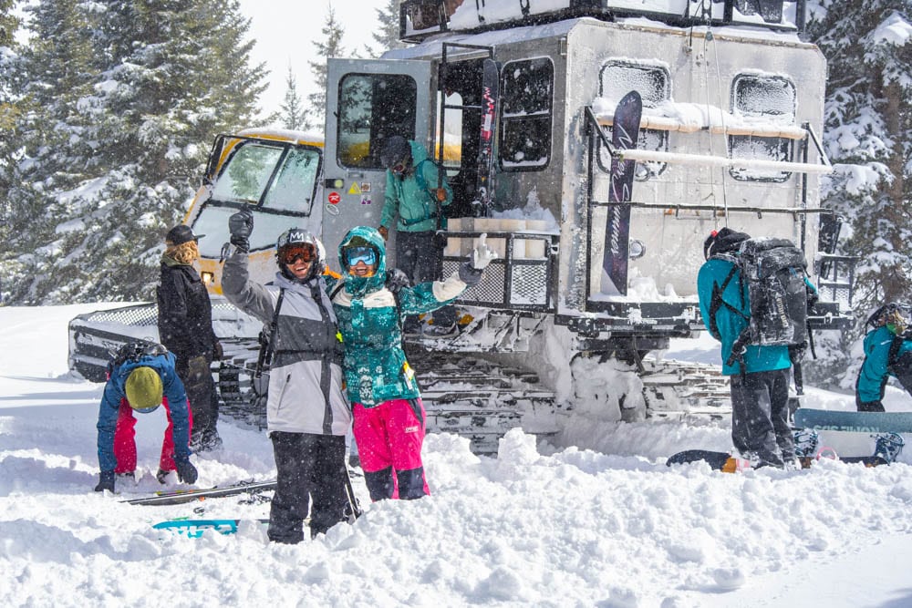 Two people in the group posing by the snowcat