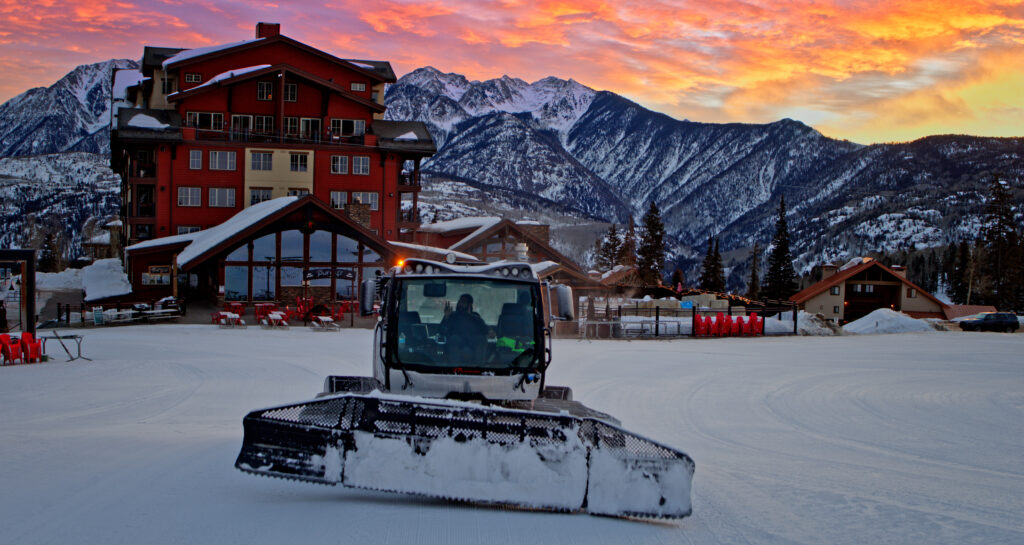 Employee in a snowcat during sunset