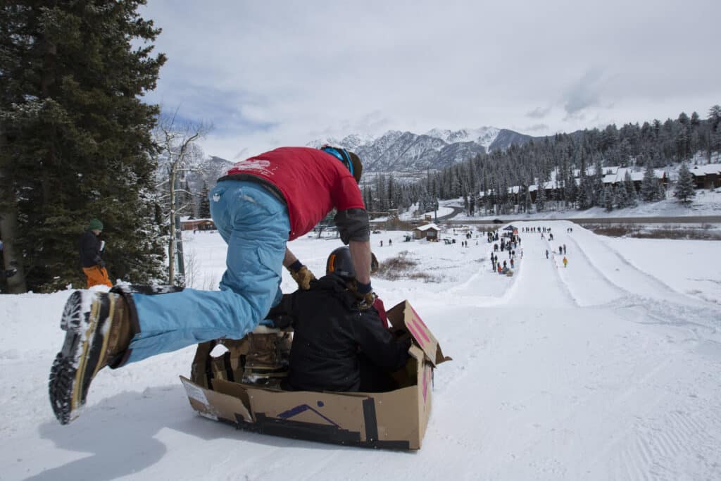 Dad pushing son down the tubing hill