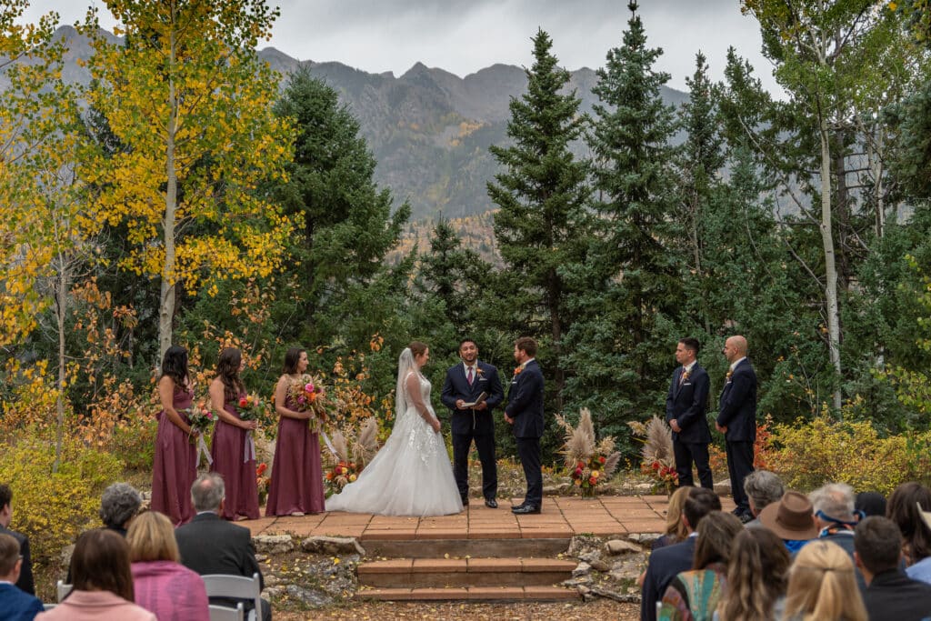 A bride and groom participate in a wedding ceremony in an alpine setting