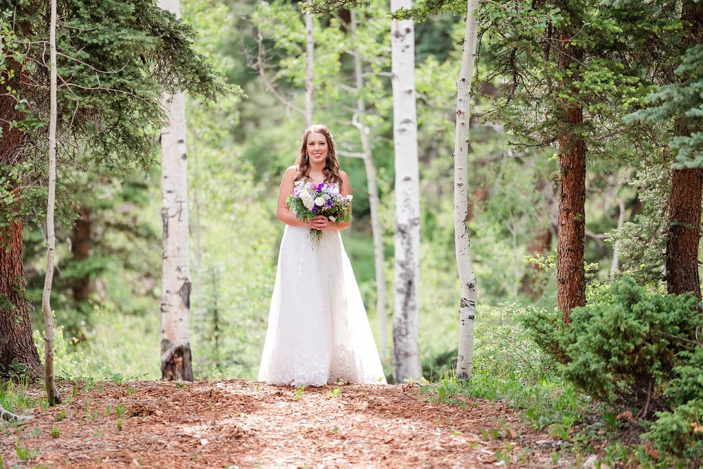 a bride walks in a forest with her bouquet