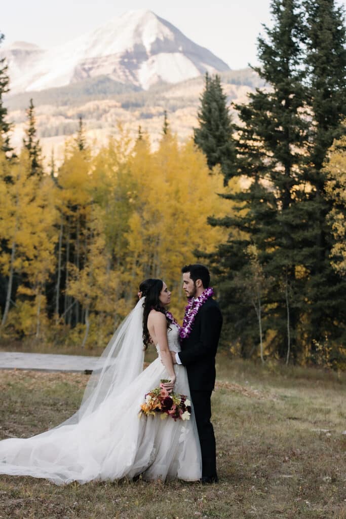 A bride and groom stand together with Engineer Mountain in the background