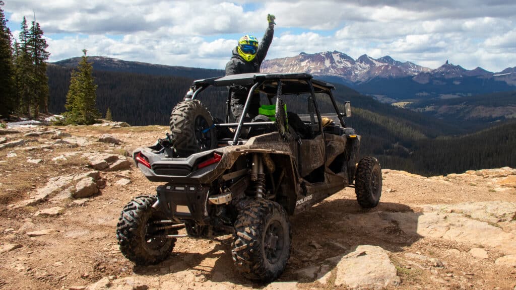 A person punches a fist in the air from the seat of RZR