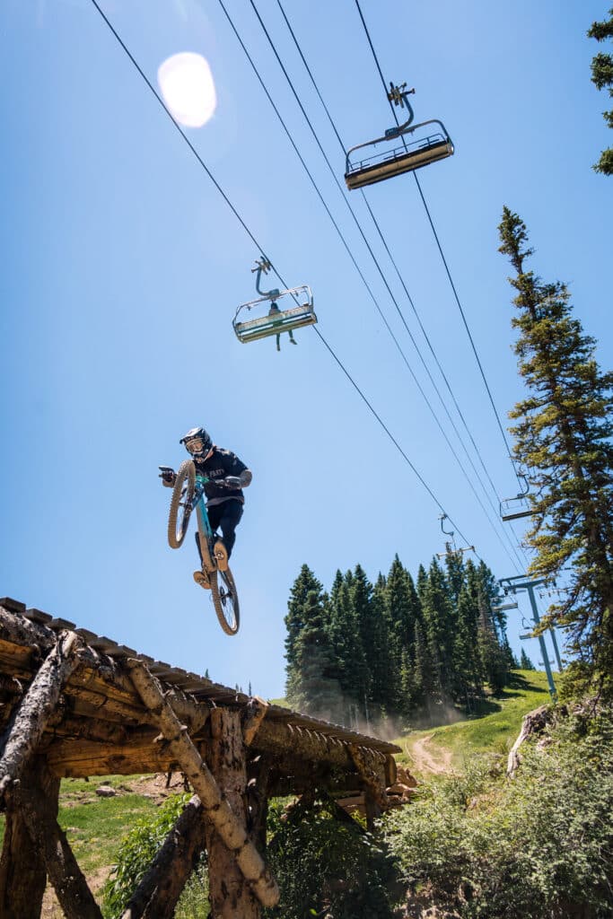 A mountain biker catches air under the ski lift