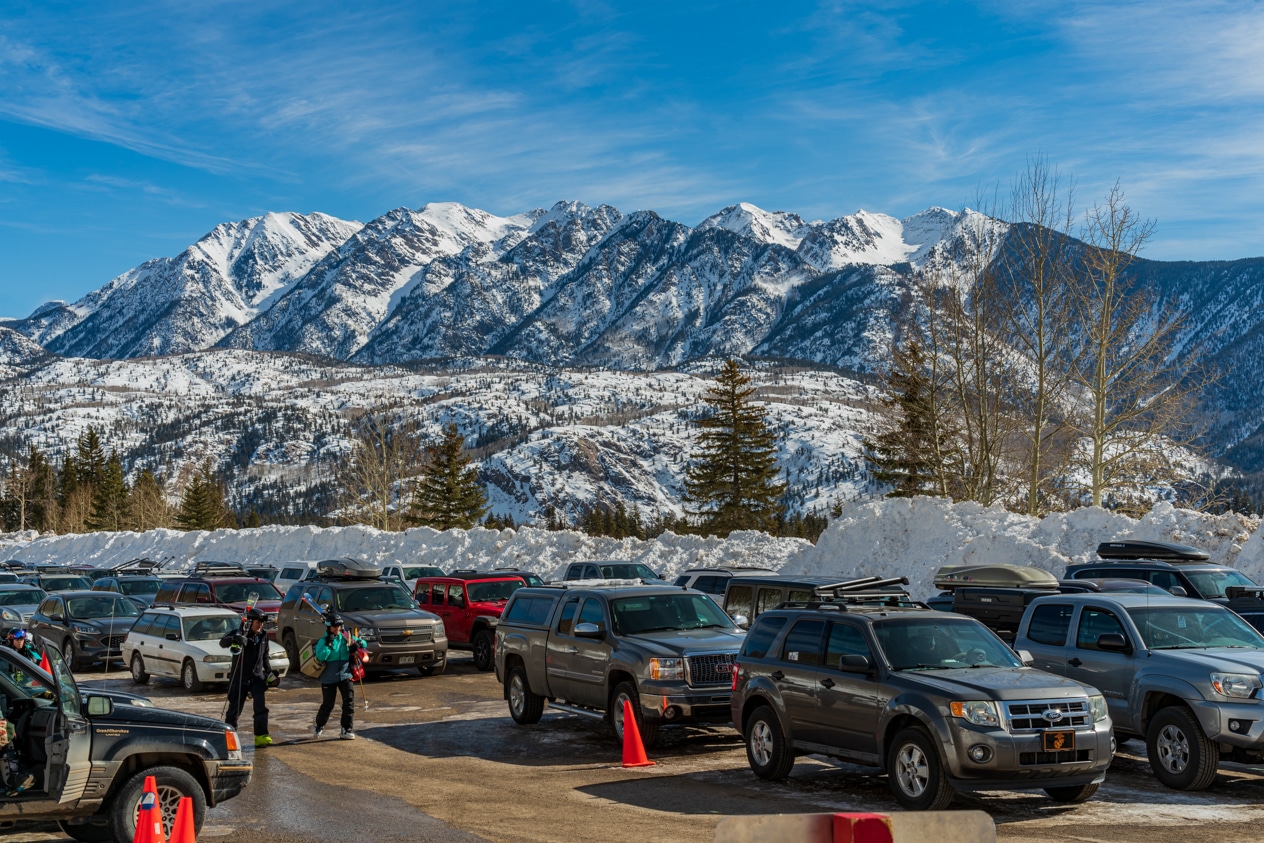 people carry their skis from the parking lot