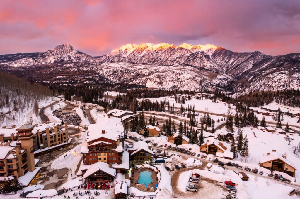 Purgatory ski resort in pink sunset light with the mountains glowing in the distance