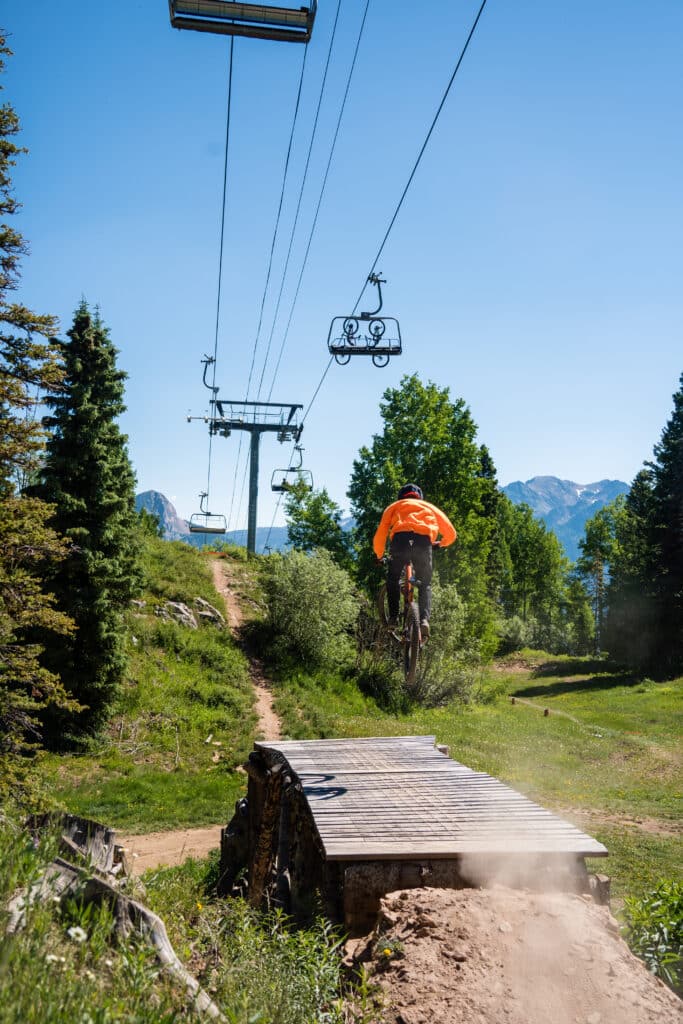 A biker in orange catches air off a ramp