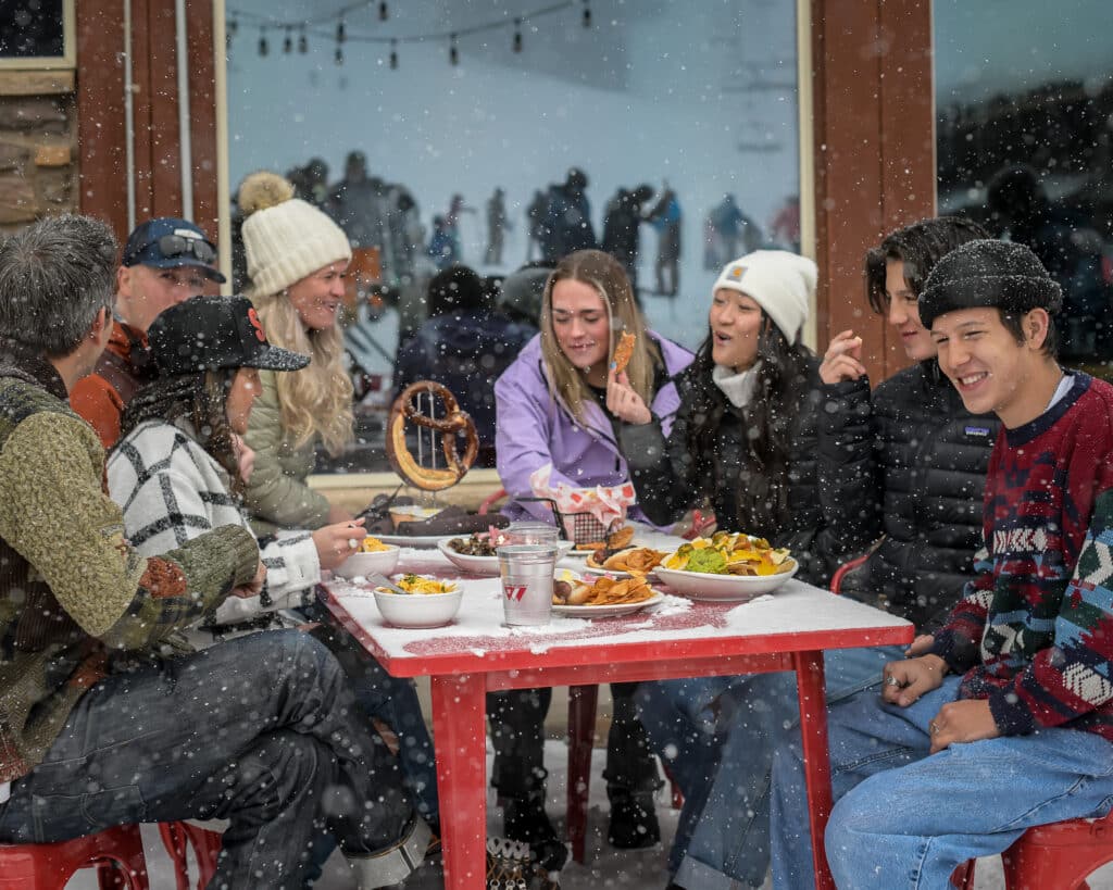 Friends gather around a table in the snow