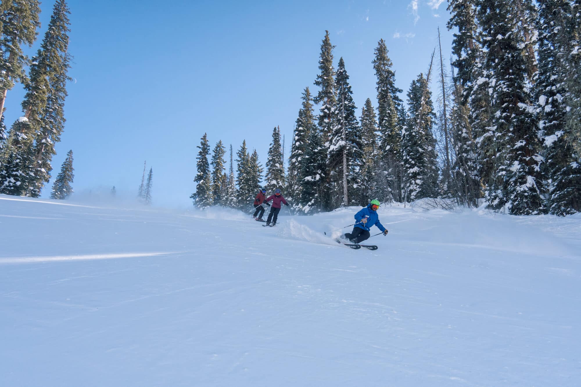 Adult ski clinic groups ski down a groomer run together