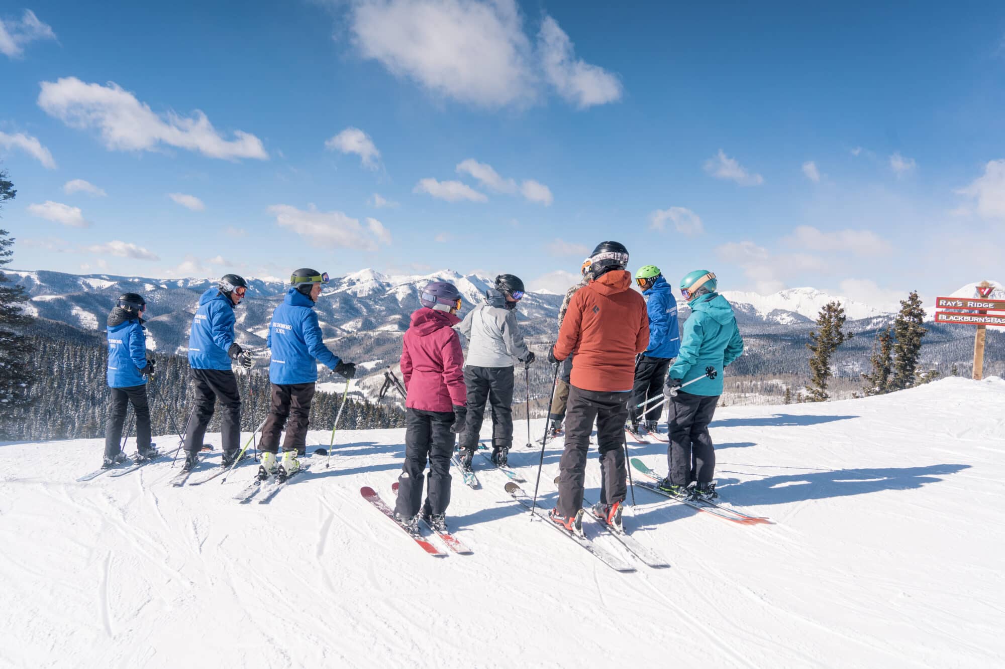 Adult ski clinic listens to instructions at a beautiful vista point