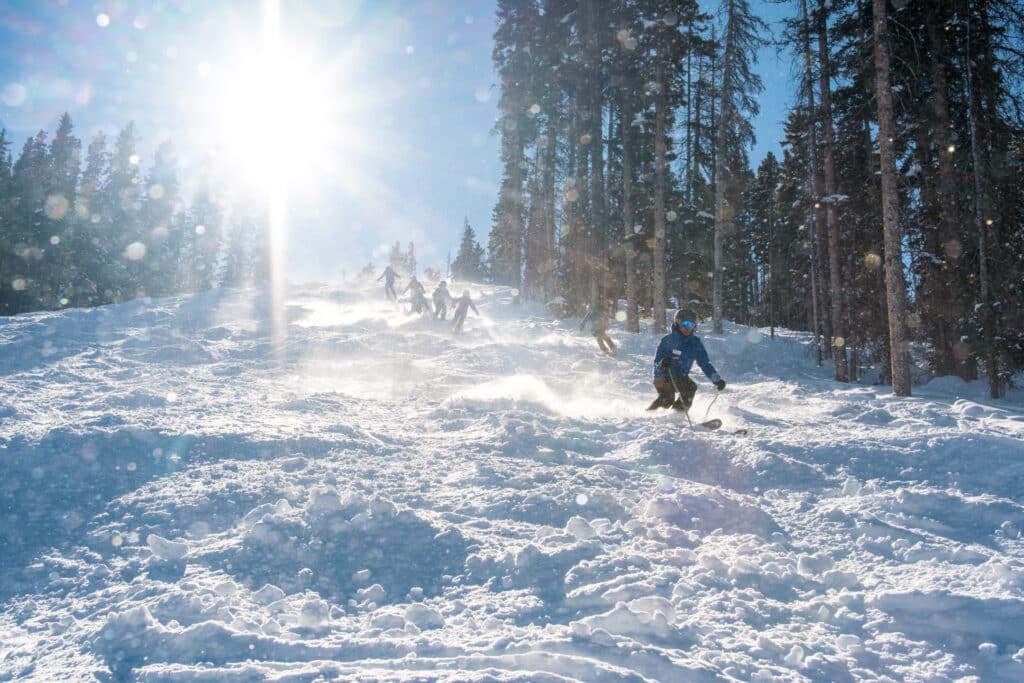 A ski instructor lead students down a bumpy run