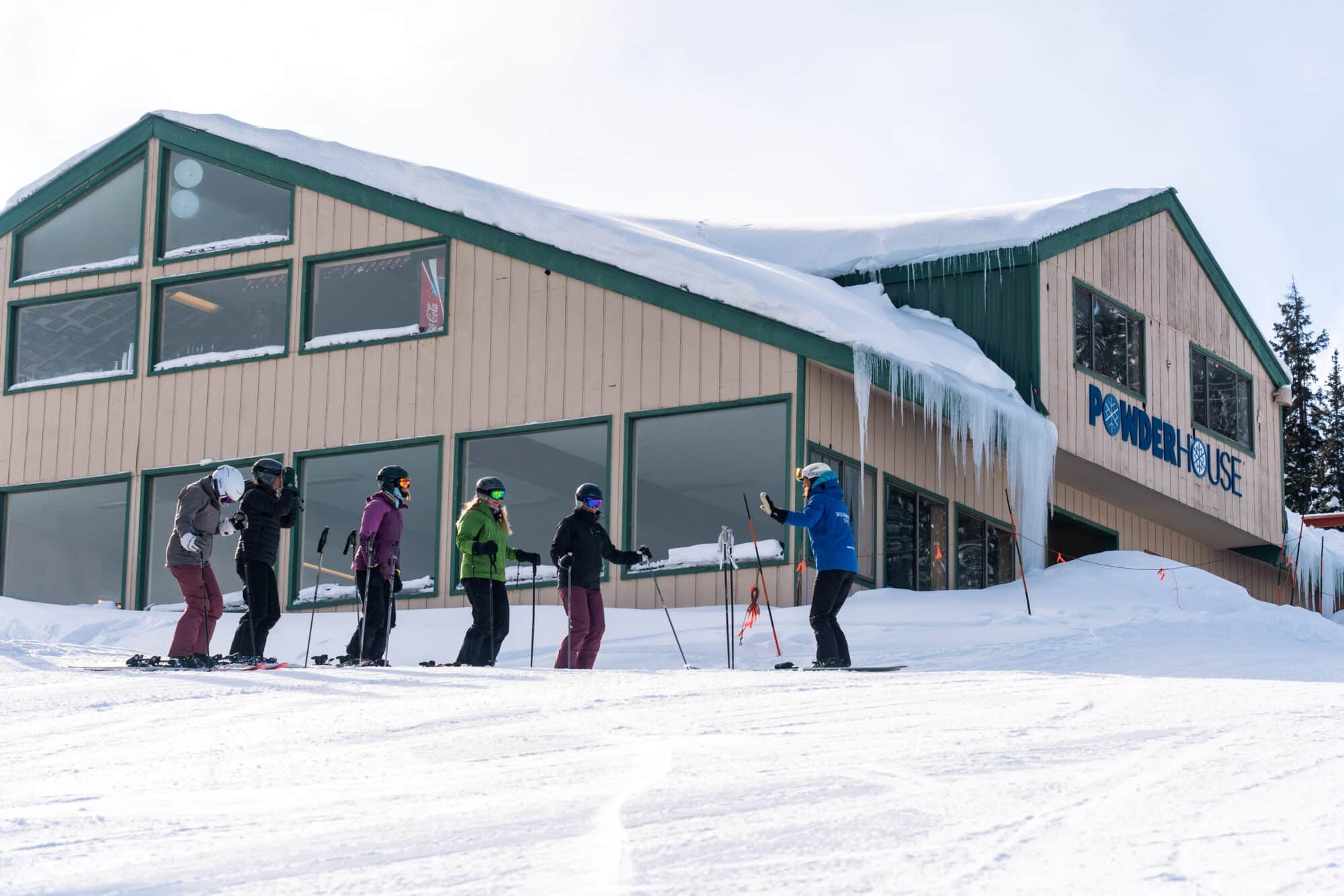 Adult ski clinic listens to instructions below Powder House