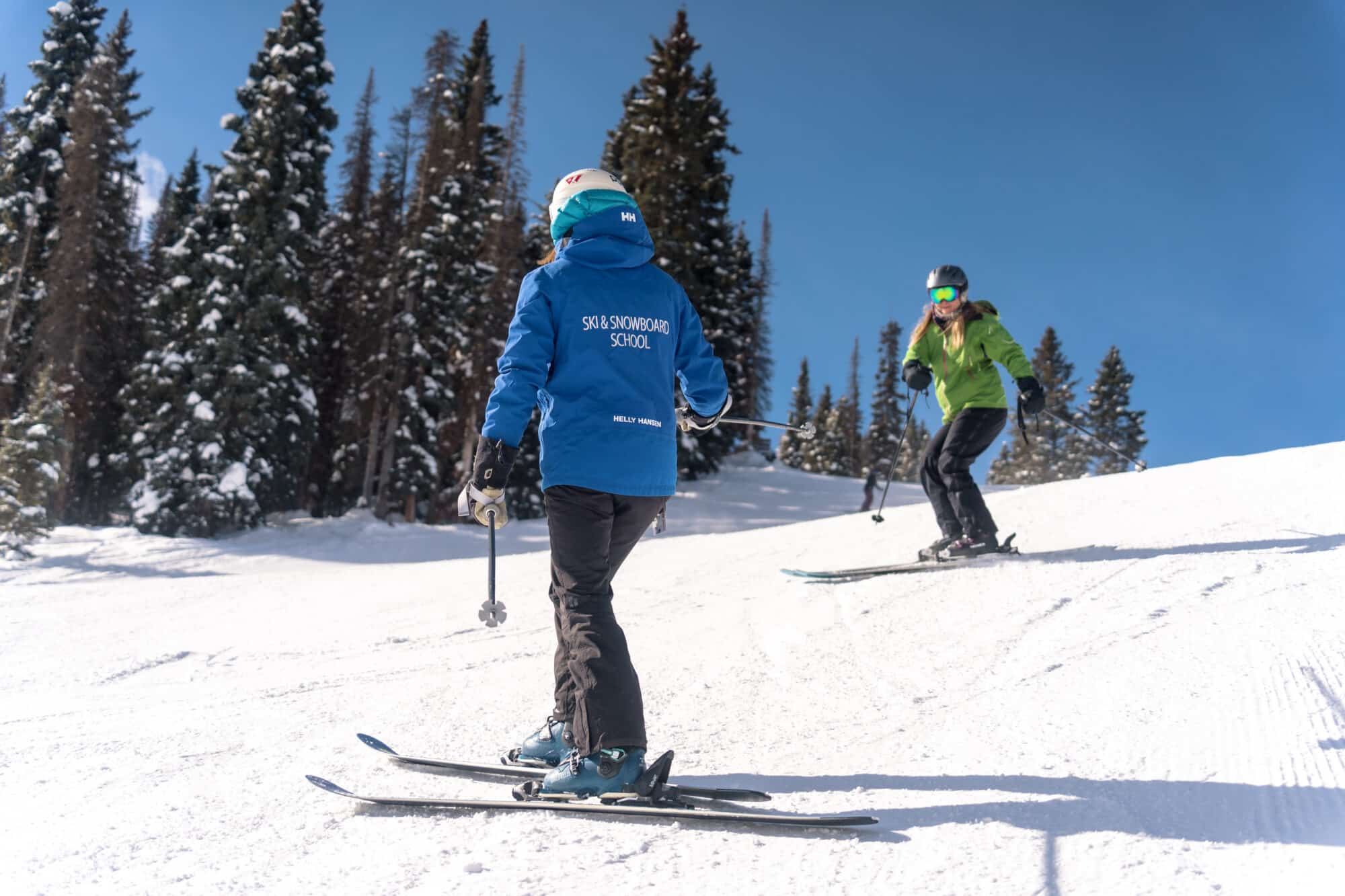 Ski instructor gives advise as student skis down