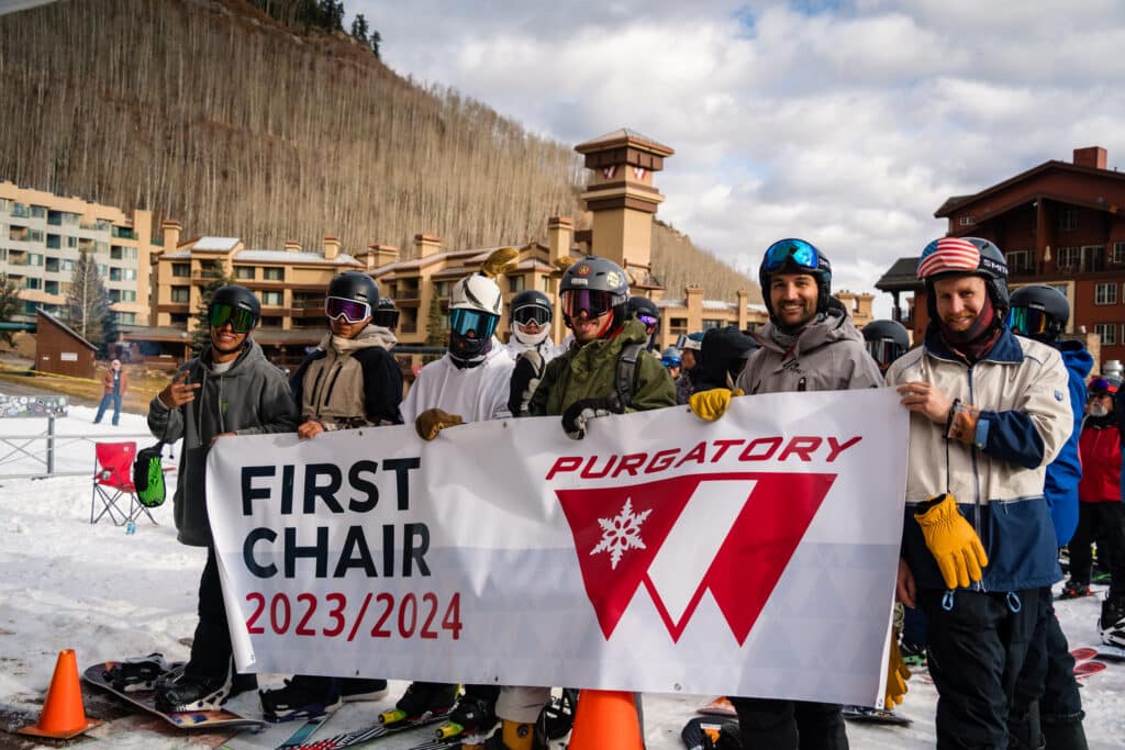 Skiers and boarders hold a banner boasting Purgatory First Chair 2023/2024