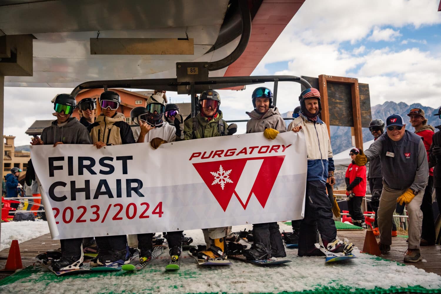 Skiers and boarders hold a banner boasting Purgatory First Chair 2023/2024
