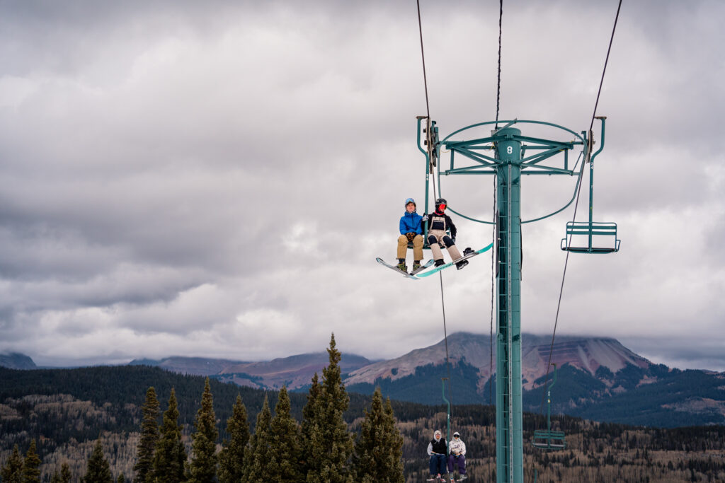 Two people ride the ski lift on opening day 2023