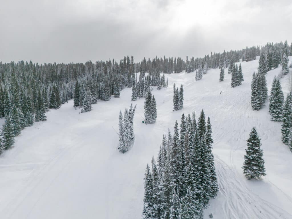The slopes off Lift 3 as viewed from the lift on a slightly cloudy day after fresh snow