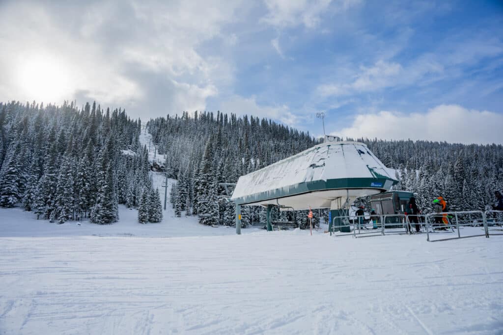 The base of Lift 3 at Purgatory with a partly cloudy ski and fresh snow on the ground.