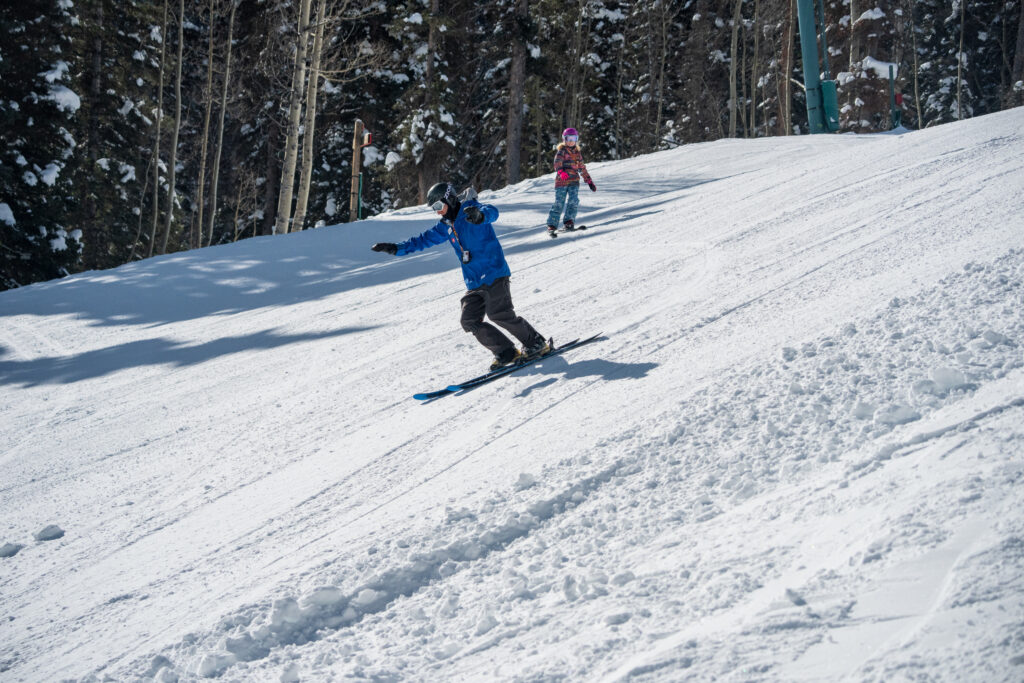 Young girl follows ski instructors controlled turns