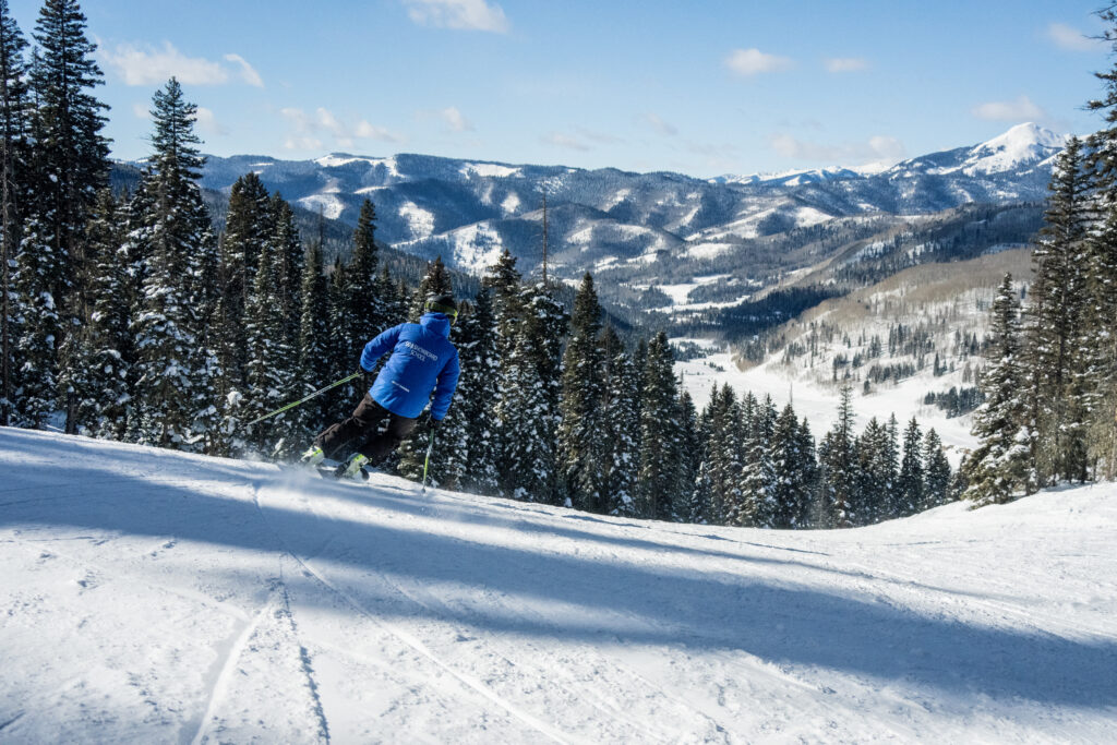 Ski instructor makes a carve turn with a beautiful scenic mountain background