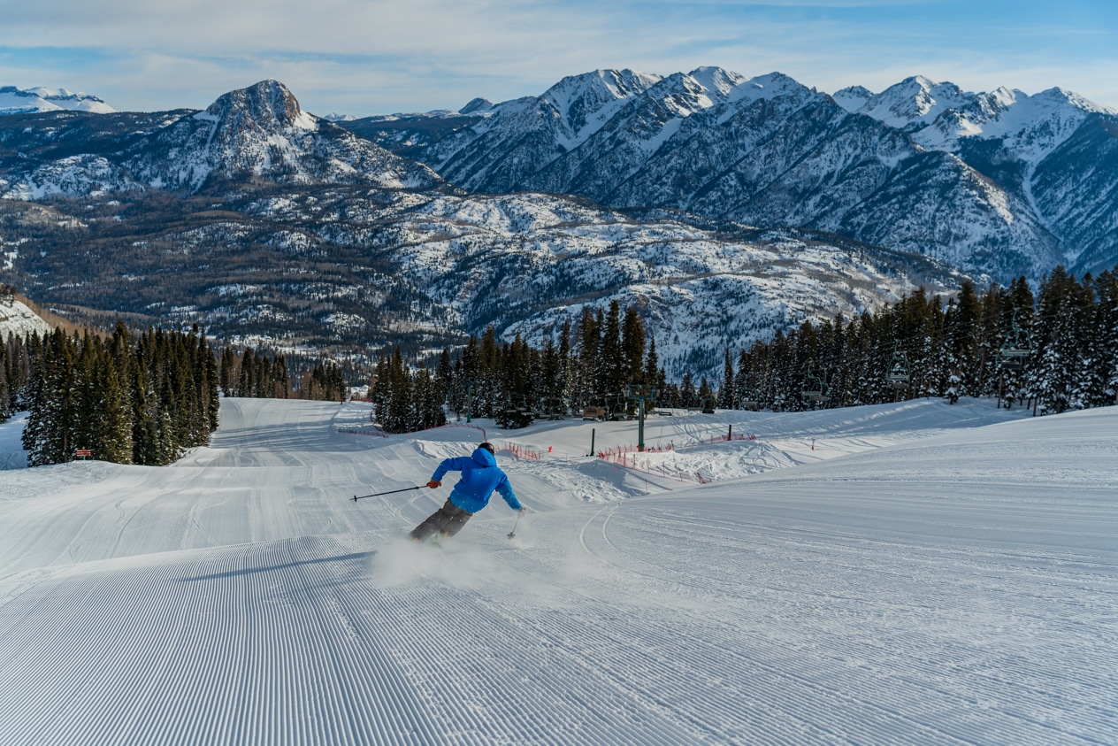 A skier in blue carves on a groomer
