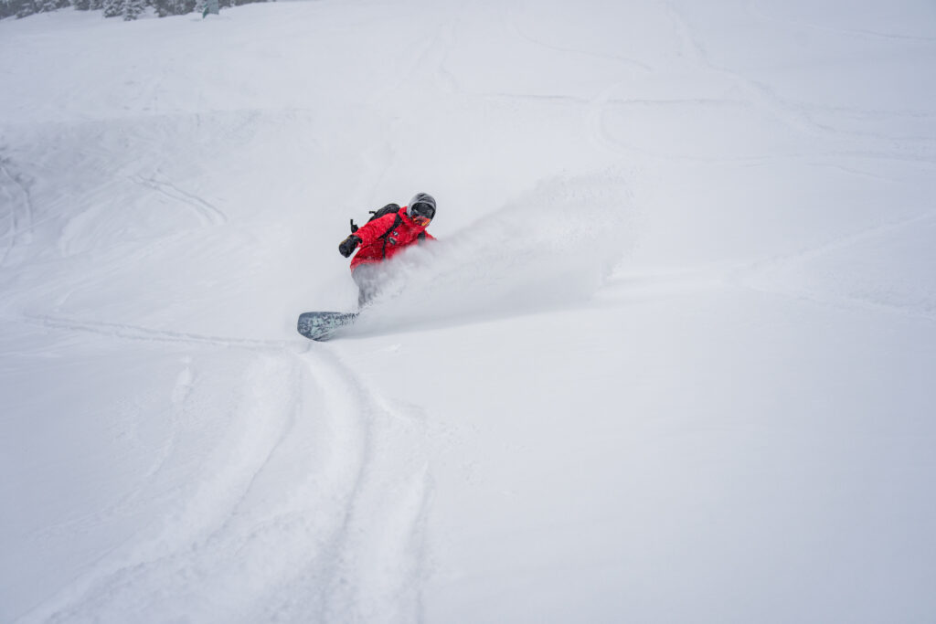 Snowboarders slashes snow in the air during a turn