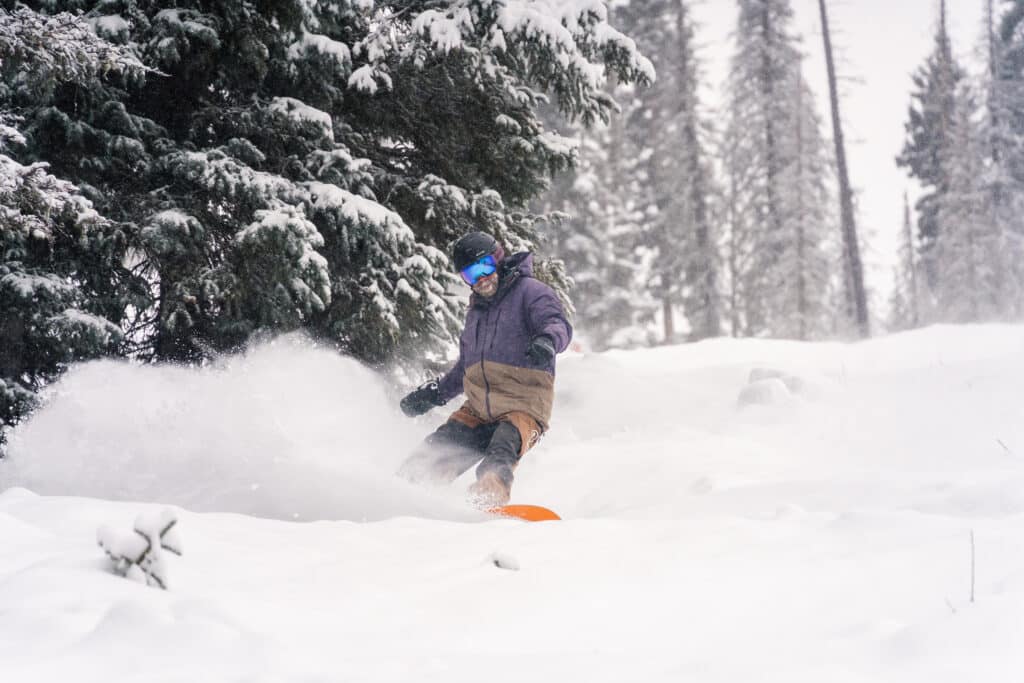 Snowboarder slashes snow into the air