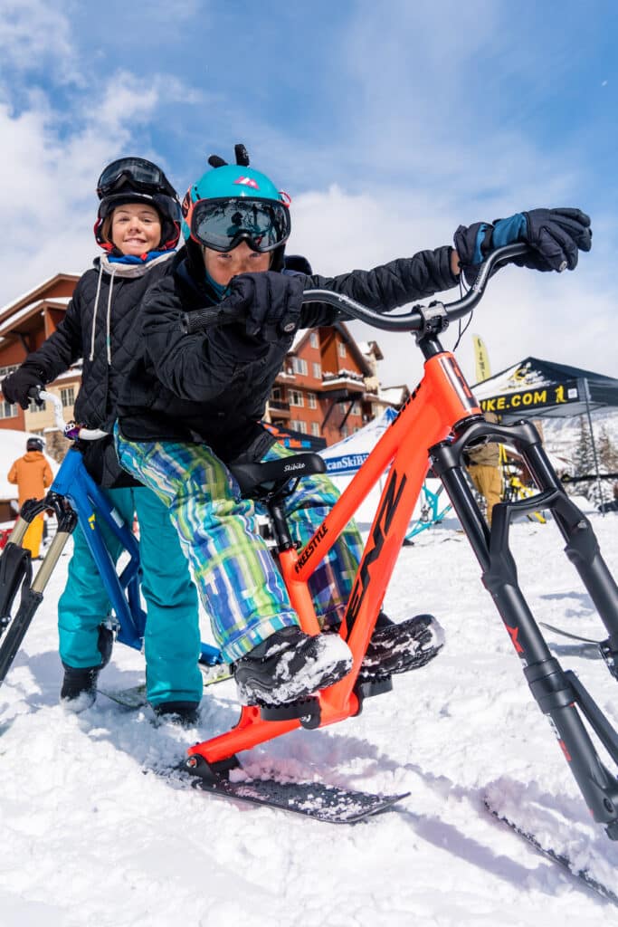 Kids pose with a ski bike
