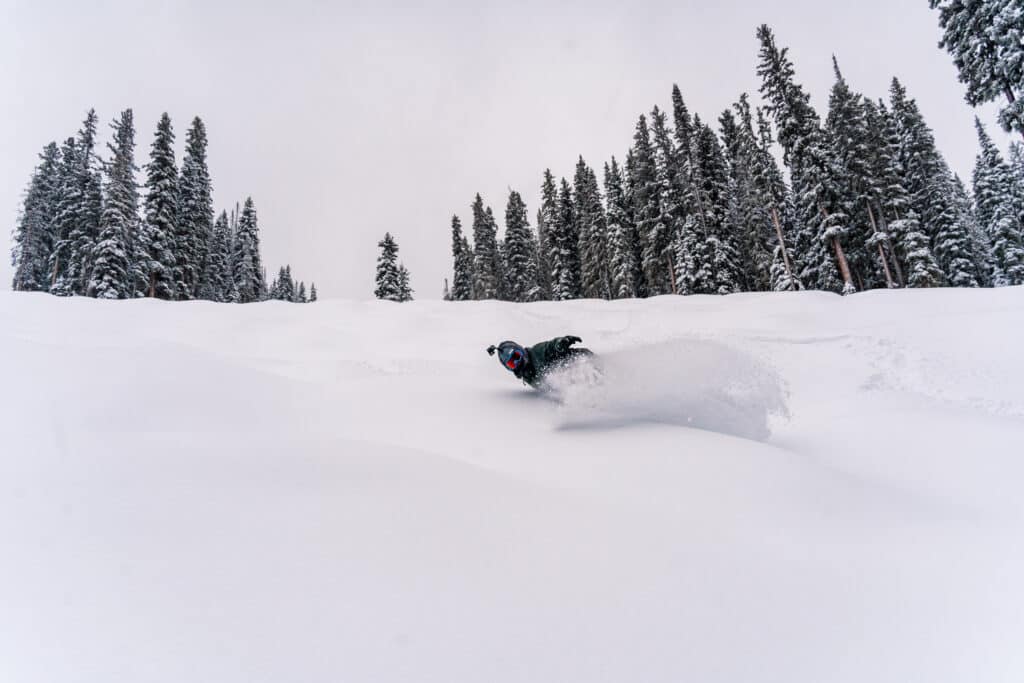 A snowboarder takes a deep turn in fresh powder