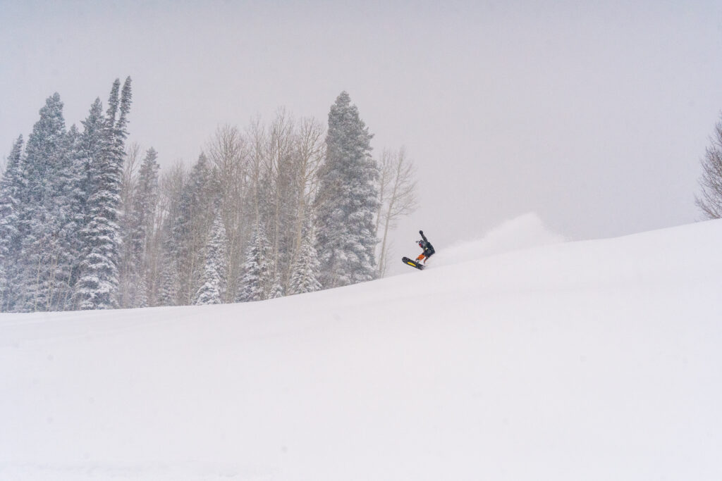 A snowboarder plays on the powdery slopes on a snowy day