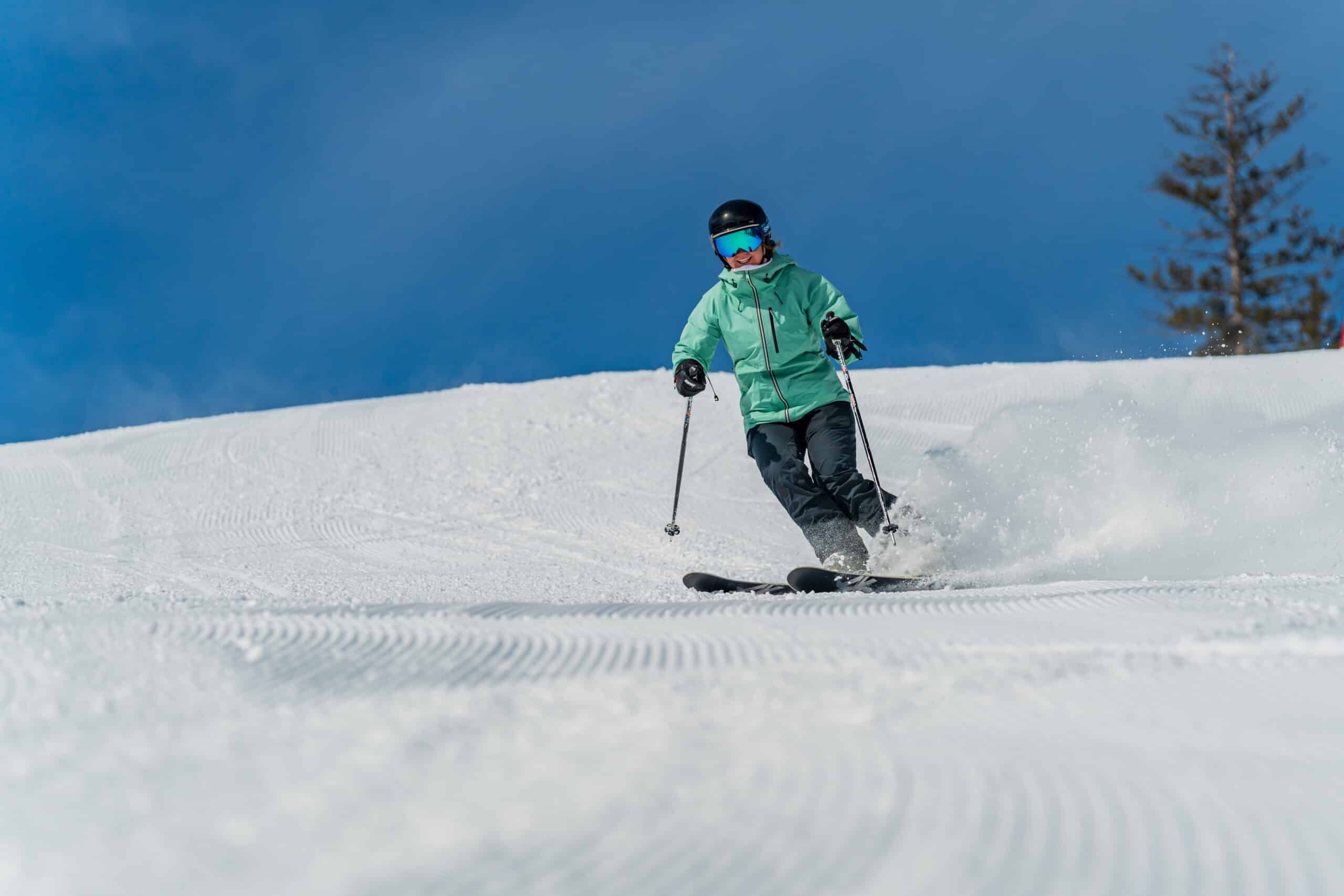 A woman skis on a groomed slope on a bluebird day