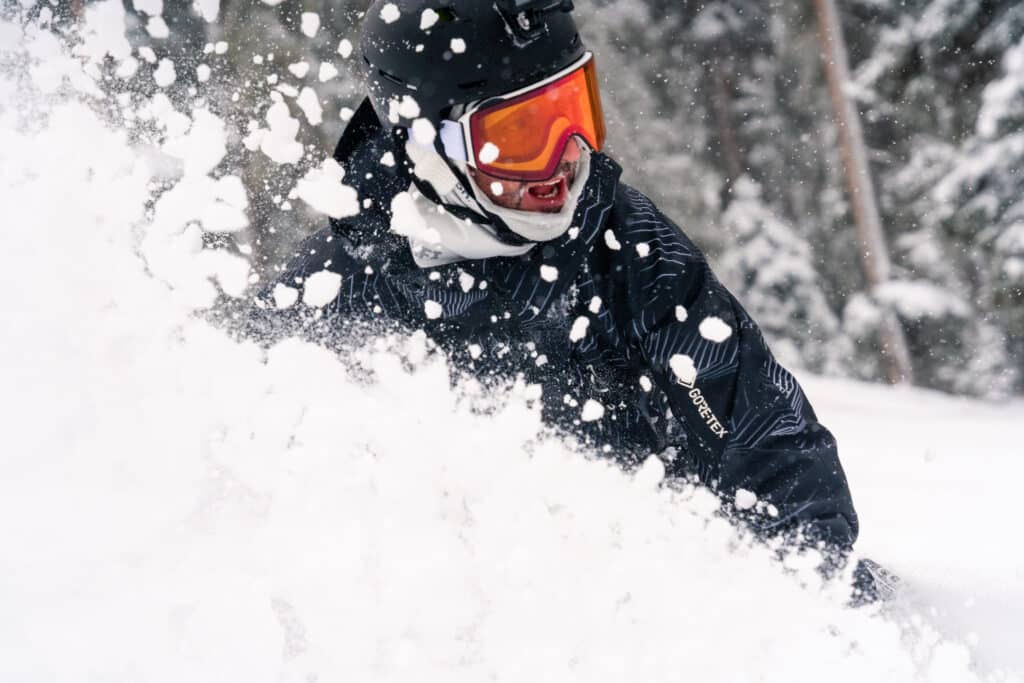 Snowboarder kicks up a cloud of snow on a powder day