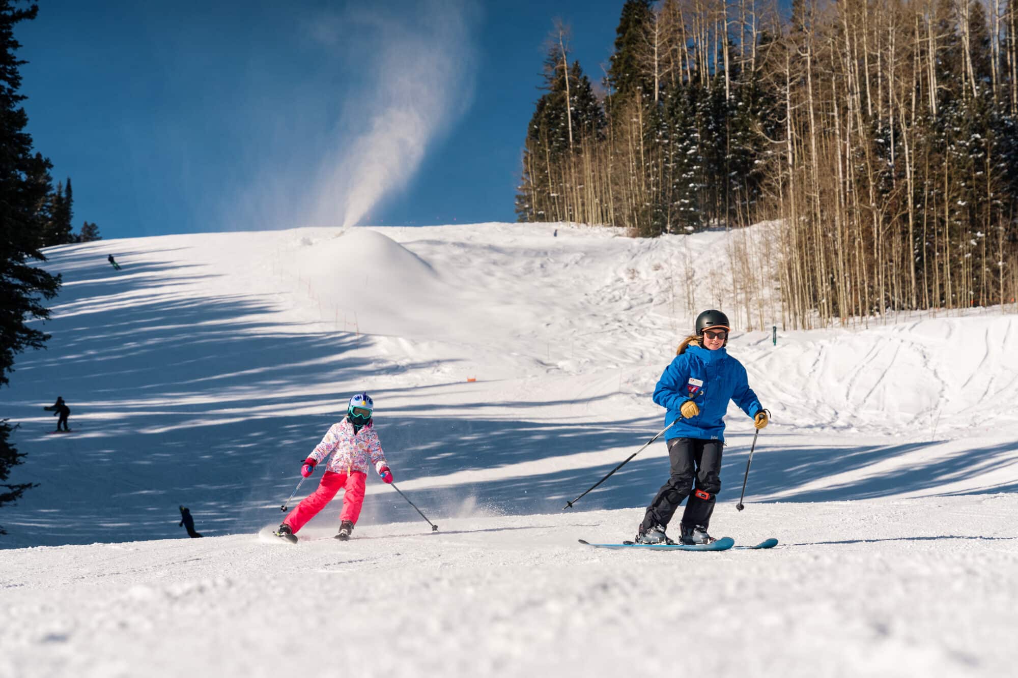 Young girl follows her ski instructors tracks down the mountain