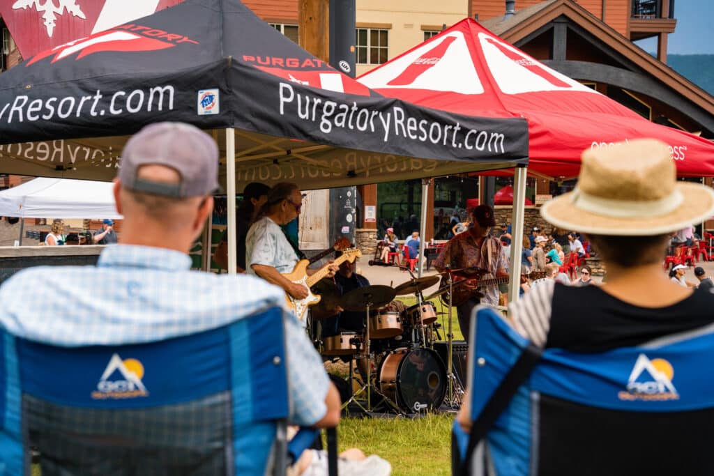 People in camp chairs listen to the band State 38 play music during summer brew 2024