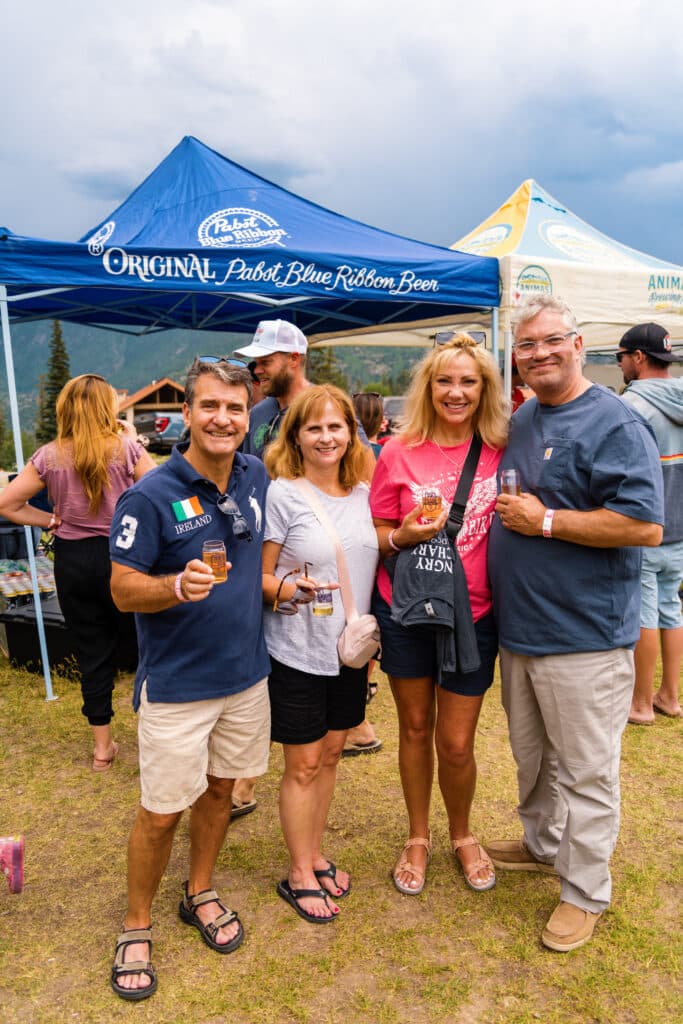 A group of people smile in front of a Pabst Blue Ribbon tent at Summer Brew 2024