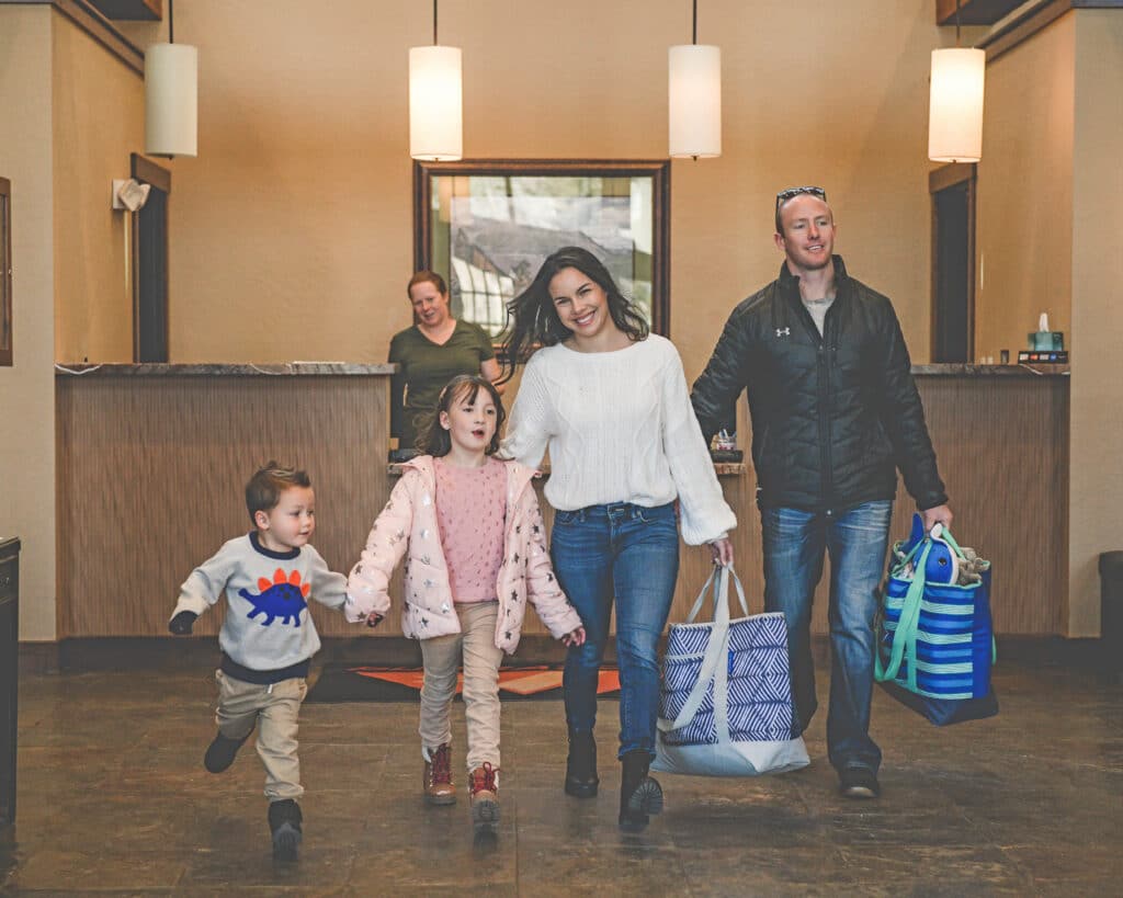 Family walking away from lodging front desk after checking in for their ski trip