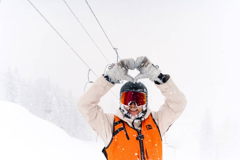 boarder makes a hand heart in the snow