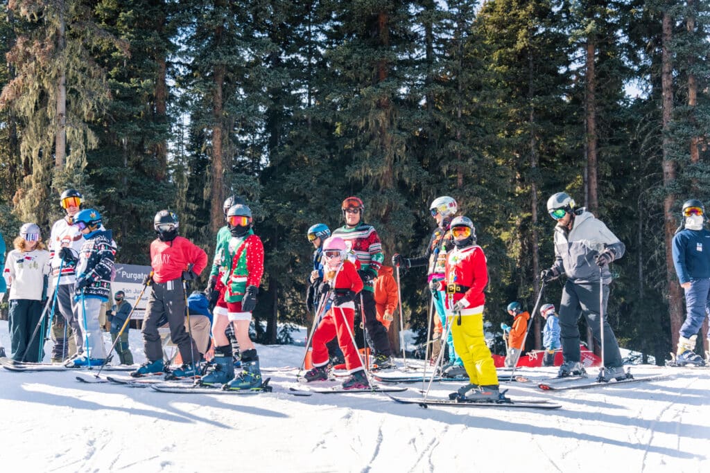 A group of skiers in Christmas sweaters pose