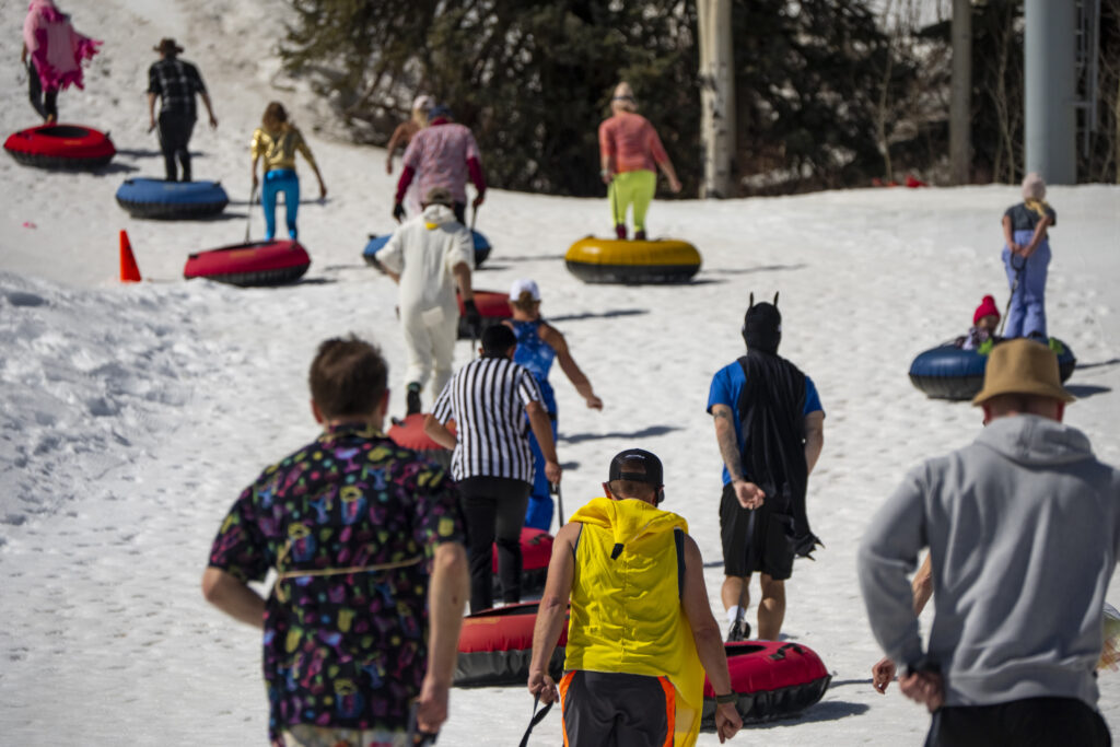 A line of costumed racers run up the hill carrying tubes