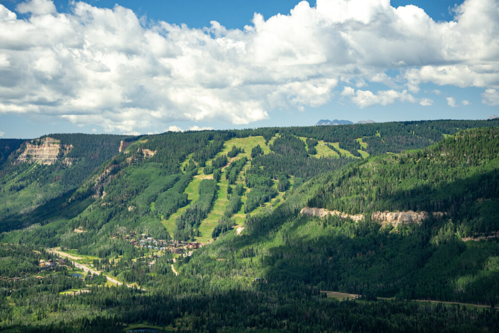 Arial drone image looking at Purgatory Resort covered in lush green during spring