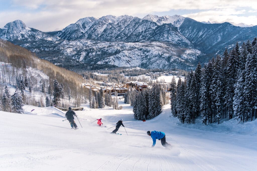 Group of friends ski down Lower Demon towards the base area at Purgatory Resort