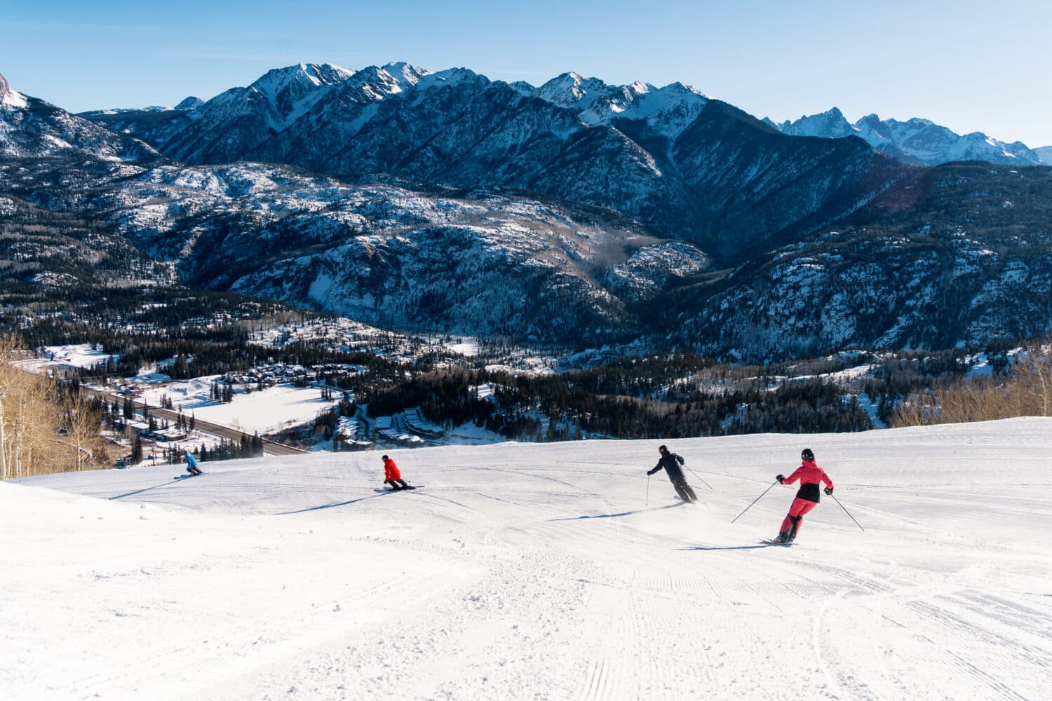 Group of skiers turn down fresh corduroy at Purgatory Resort overlooking the Needles Mountain Range